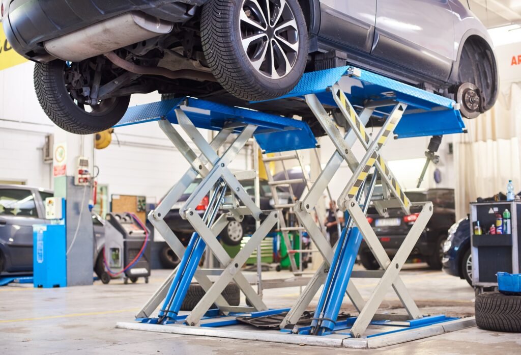 Automobile raised on lift for repairing in auto repair shop.